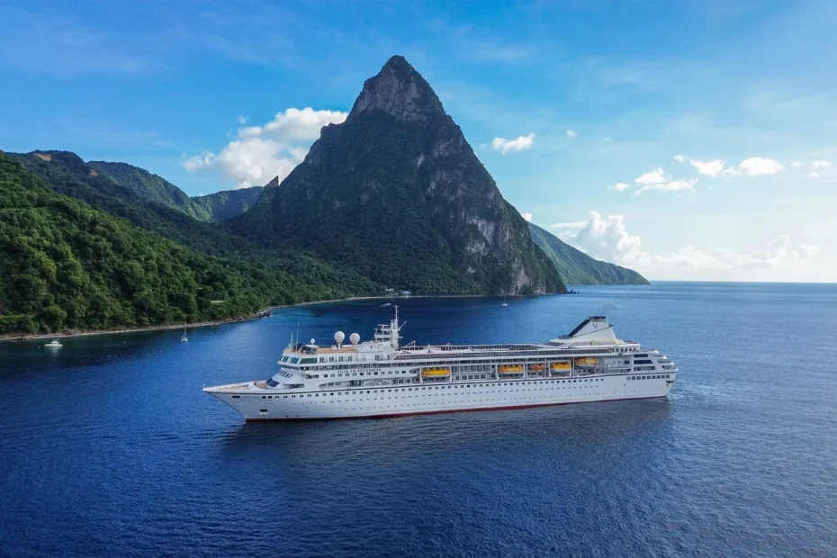 Villa Vie Odyssey cruise ship sailing near lush green mountains and tropical coastline